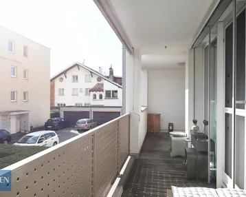 Geräumiger Balkon mit Holzboden, Sitzgelegenheiten und Blick auf die Umgebung.
