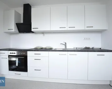 Moderne Einbauküche in Weiß mit dunkler Arbeitsplatte, ausgestattet mit Backofen und Induktionskochfeld.