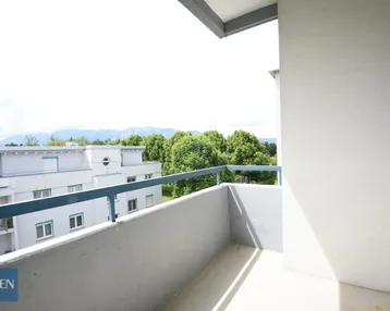 Heller Balkon mit Blick auf umliegende Gebäude und die malerische Berglandschaft.