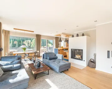 Helles, offenes Wohn-Esszimmer mit Kamin, bequemen Sofas und Zugang zur Terrasse.