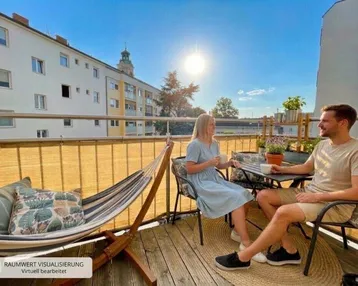Sonniger Balkon mit Holzboden, Hängematte und Sitzgelegenheiten, ideal zum Entspannen im Freien.