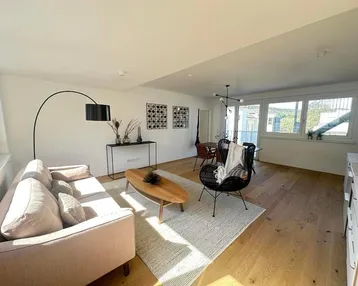 Helles, offenes Wohn-Esszimmer mit Holzboden und moderner Einrichtung.