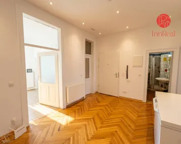 Heller Flur mit Fischgrätparkettboden und Zugang zu verschiedenen Räumen der Wohnung.