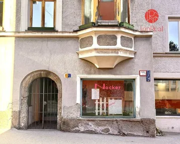 Fassade eines Altbaus mit einem Ladengeschäft im Erdgeschoss und einem markanten Erker.