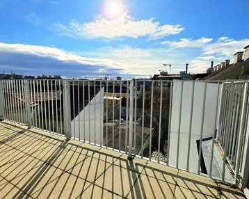 Sonnige Dachterrasse mit Fliesenboden und weitem Blick über die Stadt.
