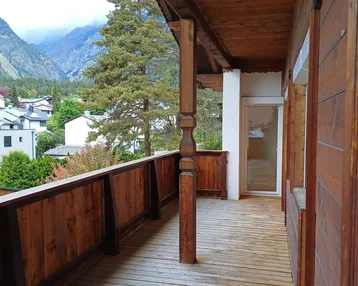 Geräumiger Holzbalkon mit traditionellen Elementen und Bergblick auf die umliegende Landschaft.