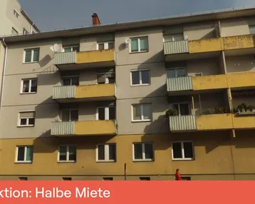 Fassade eines Mehrfamilienhauses mit Balkonen und gelben Akzenten im Sonnenlicht.