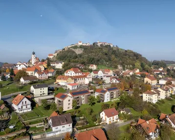 Luftaufnahme der Stadt mit Burg auf dem Hügel und den neuen Wohngebäuden in die Landschaft integriert.