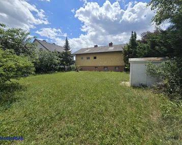 Großer, naturbelassener Gartenbereich mit Rasenfläche und kleinem Gartenhaus hinter dem Wohnhaus.