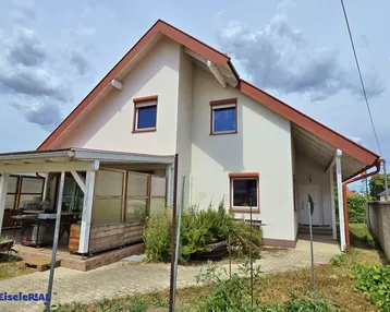 Vorderansicht des Hauses mit überdachtem Eingangsbereich und Terrasse.
