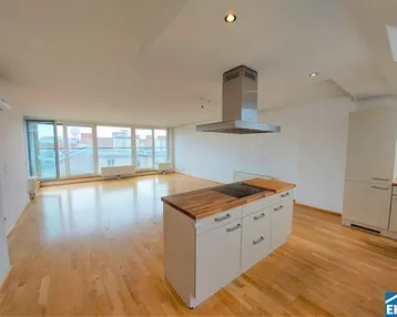 Heller offener Wohnbereich mit Holzboden, integrierter Küche und großen Fenstern mit Stadtblick.