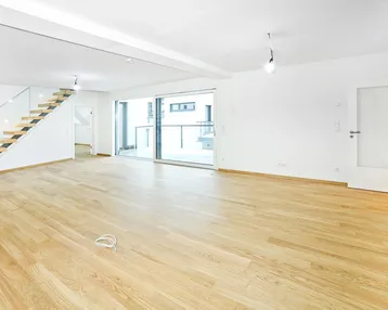 Geräumiger, heller Wohnbereich mit modernem Holzparkett, offener Treppe und Zugang zum Balkon.