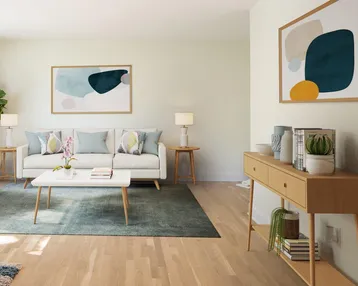 Helles Wohnzimmer mit modernem Design, Holzboden und abstrakter Kunst an den Wänden.