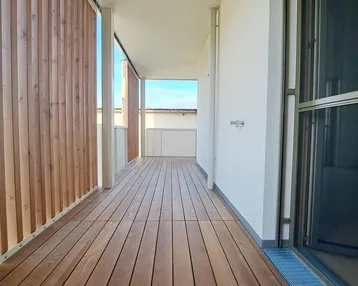 Langer Balkon mit Holzboden und seitlichen Sichtschutzelementen, ideal für Entspannung im Freien.