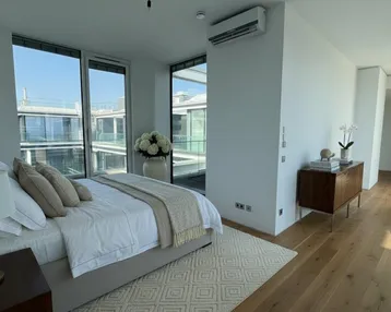Helles Schlafzimmer mit Holzboden, großen Fenstern und Klimaanlage, bietet einen Blick auf den Innenhof.