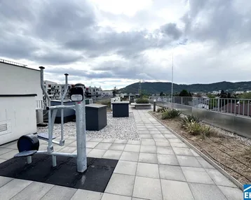 Dachterrasse mit Fitnessgeräten und weitem Blick über die Stadt und die umliegende Landschaft.