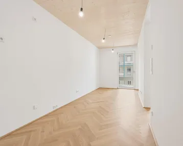Heller, leerer Raum mit Fischgrätparkett und Holzdecke, bereit zur individuellen Gestaltung.