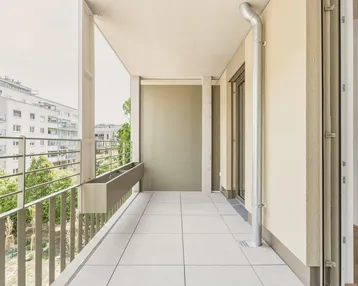 Heller Balkon mit Fliesenboden und Blick auf die umliegenden Gebäude und Grünflächen.