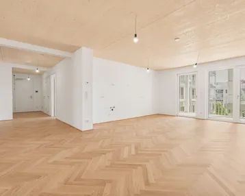 Helles, leeres Wohnzimmer mit Fischgrätparkett und Holzbalkendecke, bereit zur individuellen Gestaltung.