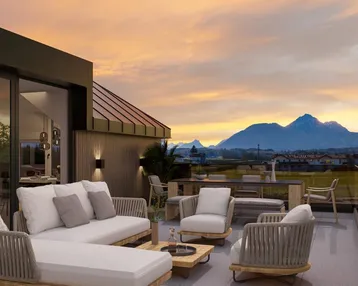Große möblierte Dachterrasse mit atemberaubendem Bergblick bei Sonnenuntergang, ideal zum Entspannen.