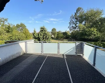 Großer Balkon mit Glasgeländer und weitem Blick ins Grüne.