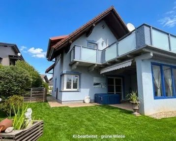 Freistehendes Einfamilienhaus mit Garten, Balkon und Terrasse unter blauem Himmel.