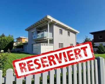 Außenansicht eines Einfamilienhauses mit Garten und einem 'Reserviert'-Banner.