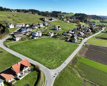 Luftaufnahme eines großen grünen Grundstücks, umgeben von Wohnhäusern und Straßen in ländlicher Umgebung.