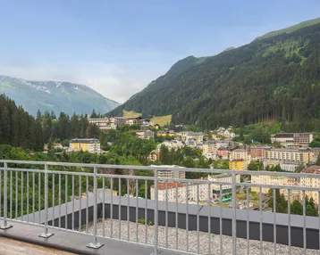 Panoramablick von einer Dachterrasse auf ein Bergdorf und die umliegende Alpenlandschaft.