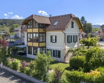 Charmantes Haus mit traditioneller Architektur, umgeben von einem gepflegten Garten und grüner Landschaft.