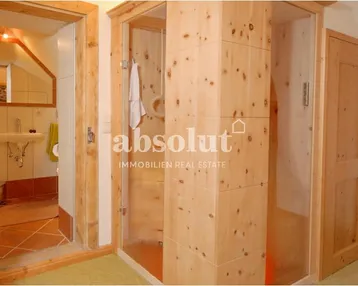 Rustikales Badezimmer mit Holzelementen und einer modernen Duschkabine, passend zum alpinen Stil.