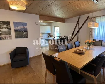 Geräumiger Wohn-Essbereich mit Holzboden, Holzbalkendecke und rustikalen Dekorationen.
