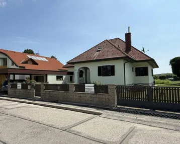 Einfamilienhaus mit gepflegtem Vorgarten und Zaun, sichtbar von der Straße aus.