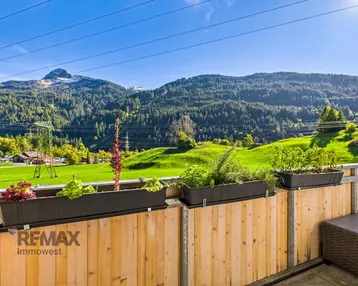 Balkon mit Holzboden und Blumenkästen bietet einen weiten Blick auf die umliegende Berglandschaft.