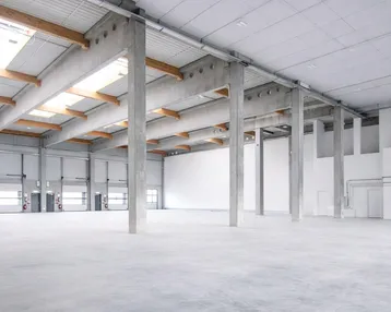 Geräumige, helle Lagerhalle mit hohen Decken, Betonstützen und mehreren Rolltoren für Anlieferung und viel Tageslicht.
