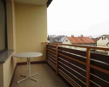 Kleiner Balkon mit Tisch und Blick auf die umliegenden Häuser und Dächer.