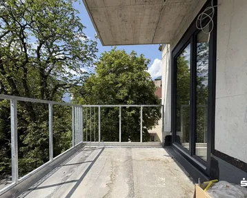 Unfertiger Balkon mit Metallgeländer und Blick ins Grüne, bereit für den weiteren Ausbau.