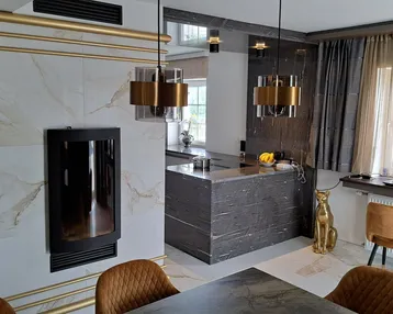 Eleganter Essbereich mit Kamin, dunklem Esstisch und goldenen Akzenten.