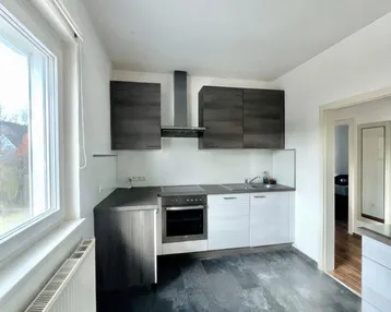 Moderne Küche mit dunklen Oberschränken, hellem Unterbau und Blick ins Grüne.