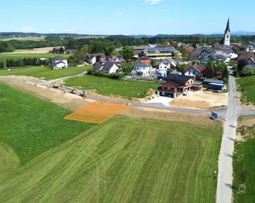 Luftaufnahme eines Baugrundstücks in ländlicher Umgebung mit Blick auf das Dorf und die Kirche.