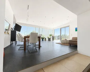Heller, offener Wohn- und Essbereich mit großen Fenstern, Zugang zur Terrasse und modernen Möbeln.