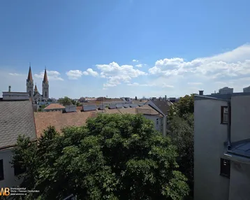 Blick über die Dächer der Stadt mit Kirchtürmen und blauem Himmel an einem sonnigen Tag.
