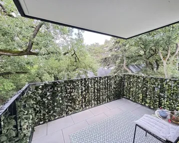 Geräumiger Balkon mit grüner Bepflanzung am Geländer und Blick ins Grüne.