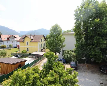 Weitblick über die Nachbarschaft mit Häusern, Bäumen und Bergen im Hintergrund.