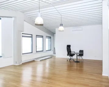 Geräumiges, helles Büro mit Holzboden, großen Fenstern und moderner Deckenverkleidung.