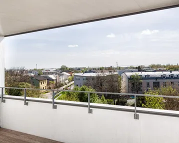Geräumiger Balkon mit Holzboden und weitem Blick über die Stadt und die umliegende Landschaft.