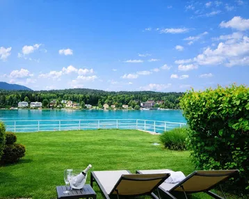 Gepflegter Rasenbereich mit Liegestühlen und atemberaubendem Blick auf den See und die umliegende Landschaft.