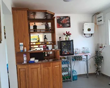 Raum mit einer Holzbar, kleinem Kühlschrank und einem an der Wand montierten Solarwechselrichter.