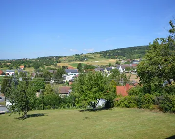 Weitläufiger Blick über die grüne Landschaft mit verstreuten Häusern und Hügeln.