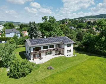 Luftaufnahme des Hauses mit Solaranlage auf dem Dach und weitläufigem grünen Grundstück.